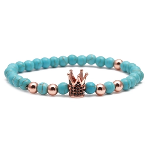 Detailed close-up of blue turquoise beads with a rose gold crown charm set with black stones