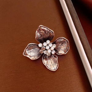 Detail of vintage flower brooch with central rhinestones and textured golden petals