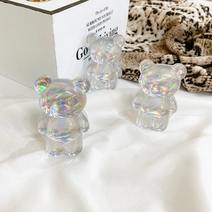 Three iridescent laser bear phone grips with a vibrant gradient finish on white fabric