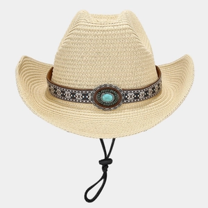 Detail of straw cowboy hat with ethnic embroidery and turquoise stone on beige woven texture