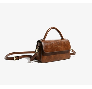 Dettaglio borsa vintage marrone con logo dorato e finitura in pelle cerata testurizzata