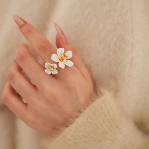 Close-up of gold-plated flower ring with yellow cubic zirconia on finger