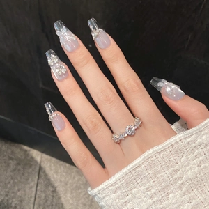 Macro detail of coffin shaped press-on nails with 3D butterfly bows and pearls