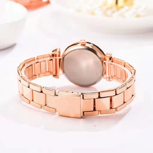 Macro detail of the rose gold watch case back and polished metal link bracelet strap