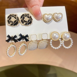 Detail of vintage flower and pearl earring set featuring camellia and bow designs