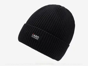 Detailed side view of black ribbed knit beanie with branded rectangle logo patch
