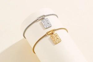 Detail view of gold and silver box chains with embossed lucky symbols on square charms
