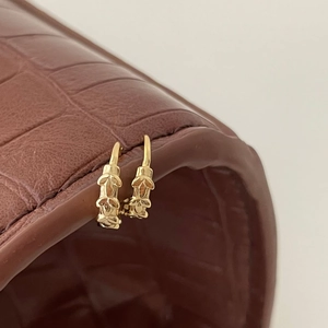 Macro detail of vintage gold hoop earrings with leaf texture on leather surface
