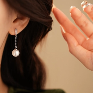 Elegant silver long drop earrings with zircons and pearl pendant worn by a model