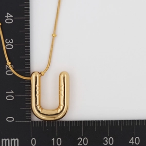 Detailed size measurement of a gold balloon-style letter U pendant necklace with a ruler