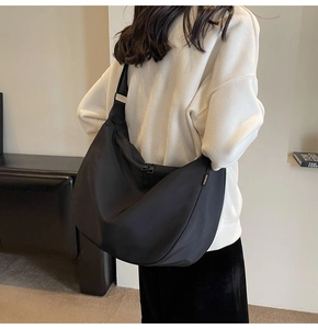 Rear view of a model wearing a large black waterproof oxford cloth crescent crossbody bag