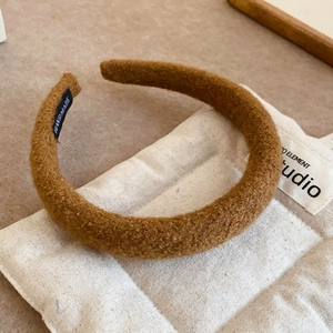Deep brown plush lamb wool headband with handmade label on quilted fabric background