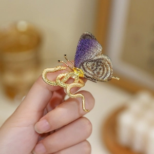 Close-up of golden snake and embroidered butterfly hair clip with fine metal details