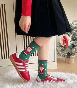 Close-up of festive green Christmas socks with Santa Claus pattern and fuzzy texture