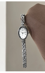 Gros plan d'une montre ovale vintage argentée avec chiffres romains et bracelet métal