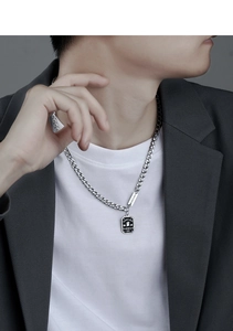 Detail of silver Cuban chain necklace featuring a square pendant with Good Luck engraving