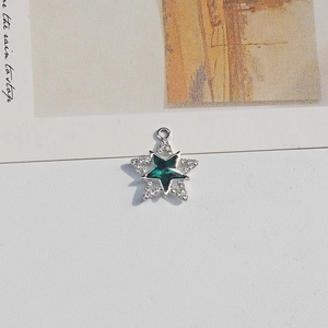 Close-up of a star-shaped pendant with dark green gemstone and pavé white rhinestones