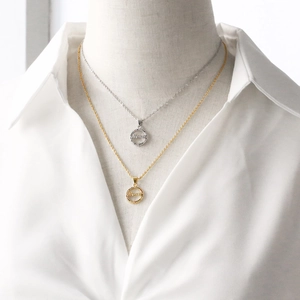 Detail of gold and silver Mama pendant necklaces with zircon circles on white shirt