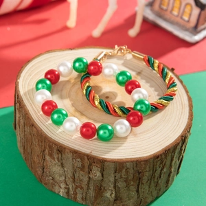 Detailed view of Christmas red and green pearl bracelets and woven cords on a wooden base