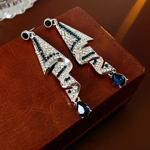 Macro shot of silver drop earrings with blue crystals on a brown leather jewelry box