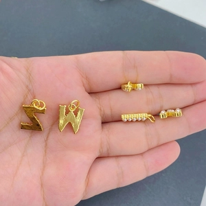 Detailed close-up of golden alphabet pendants W and Z with elegant inlaid pearls