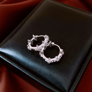 Vue macro de boucles d'oreilles fleurs en argent et zircon sur boîte en cuir noir