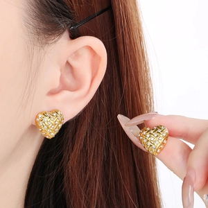 Detailed close-up of gold heart-shaped stud earrings with sparkling pavé crystal accents