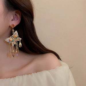 Close-up of elegant gold butterfly tassel earrings with crystals on female model