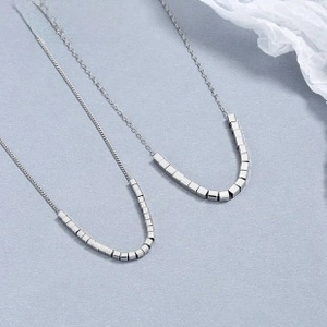 Detalle de cuentas cúbicas de plata de ley 925 en cadenas finas de estilo minimalista