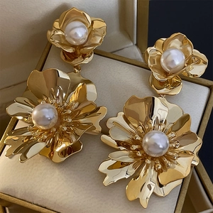 Vue détaillée de boucles d'oreilles fleur dorée avec perles sur un écrin à bijoux