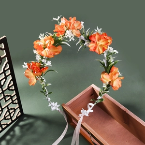 Detailed view of orange floral wreath headband with green leaves on a wooden box