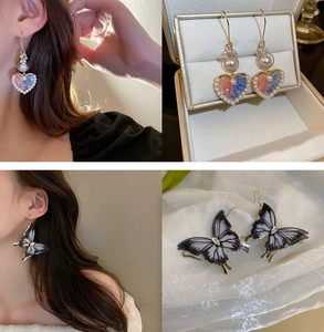 Detail view of heart pearl and large butterfly tassel drop earrings on model