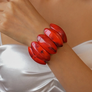 Detail of red acrylic chunky bracelet with marble ink pattern on a silk sleeve