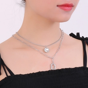 Detail of silver layered necklace featuring rhinestone pendant and textured rectangle charm