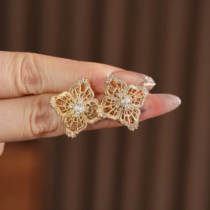 Macro shot of gold floral earrings with intricate hollow patterns and zircon crystals