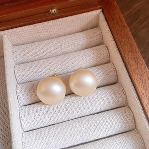 Close-up of champagne pearl stud earrings with matte finish in a jewelry box