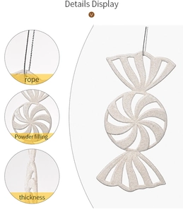 Detail view of candy-shaped Christmas ornament with white glitter texture and hanging rope