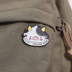 Détail de la broche vache en émail avec texte humoristique sur sac en toile vert
