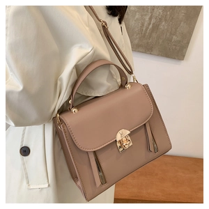 Detail of mocha faux leather satchel featuring gold lock and side zipper accents
