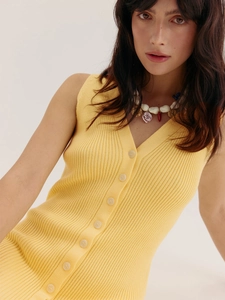 Détail de la texture en maille côtelée jaune et du col en V avec boutons sur la robe