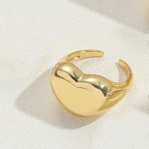Detailed close-up of a golden heart-shaped open ring with a smooth metallic finish