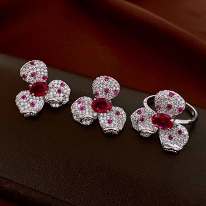 Detailed macro of flower-shaped silver earrings and ring set with zircon and rubies