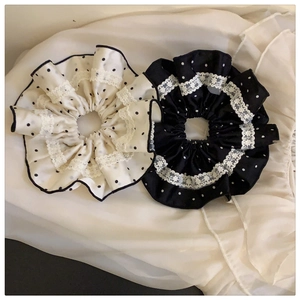 Detail of polka dot satin scrunchies with delicate lace edges on pleated fabric