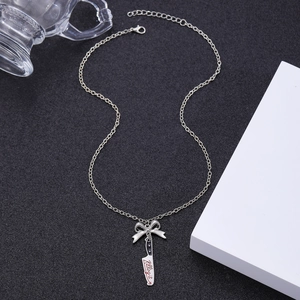 Macro shot of silver necklace featuring a bow, kitchen knife pendant, and Killing it text