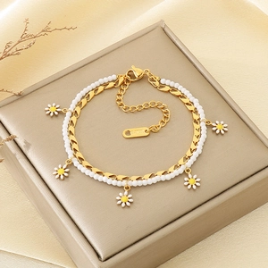 Detail of double-layer stainless steel bracelet featuring white daisy charms and pearls