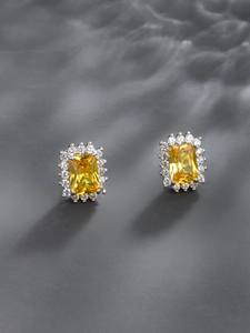 Macro view of emerald-cut yellow crystal earrings with shimmering white halo accents