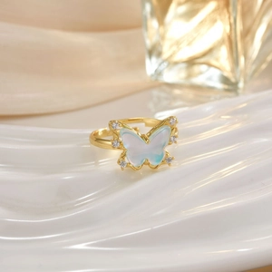 Macro shot of gold butterfly ring featuring white shells and crystal zircons