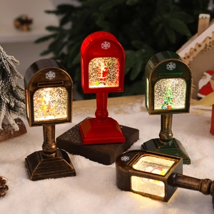Close-up of lighted Christmas mailbox lanterns with Santa figures on artificial snow