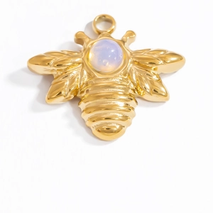 Macro shot of gold-plated bee pendant with white opal gemstone on white background