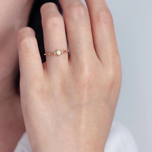Anello in oro rosa con zircone peridoto su dito di una modella donna